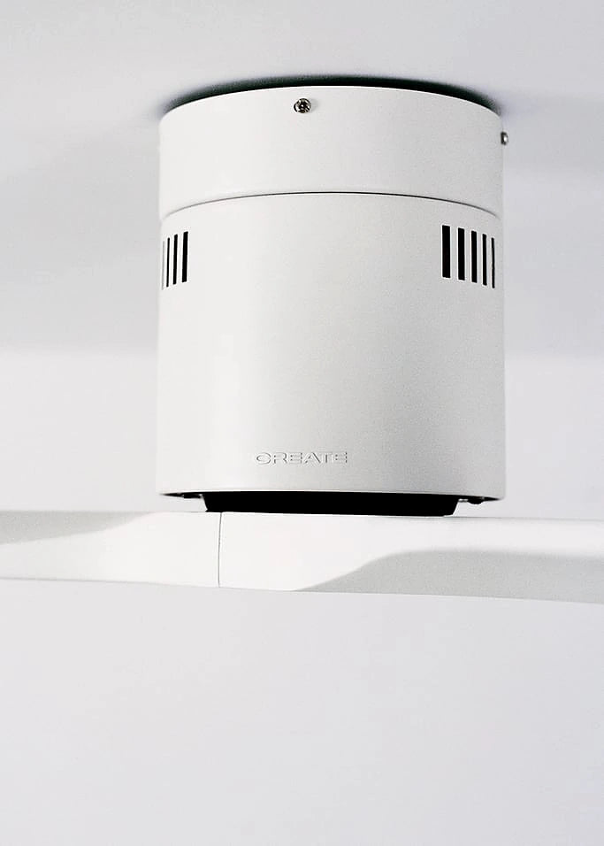 White cylindrical device of create ceiling fan on a light gray background