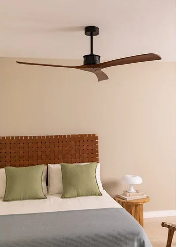 Ceiling fan above a bed with green pillows and a wooden headboard in a bedroom setting.